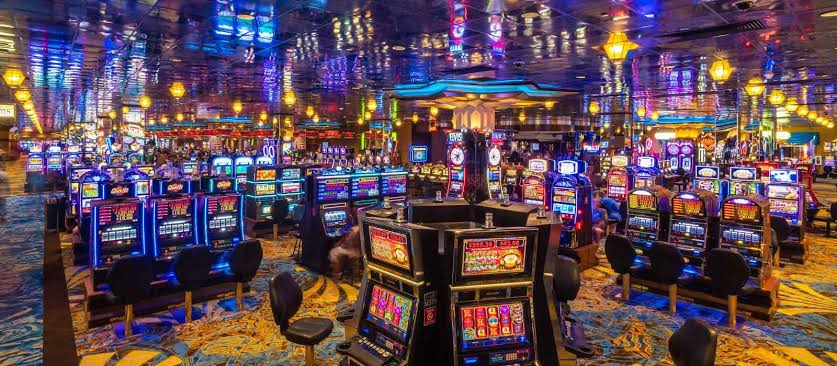 Sala de juegos con m&aacute;quinas tragamonedas encendidas en perspectiva